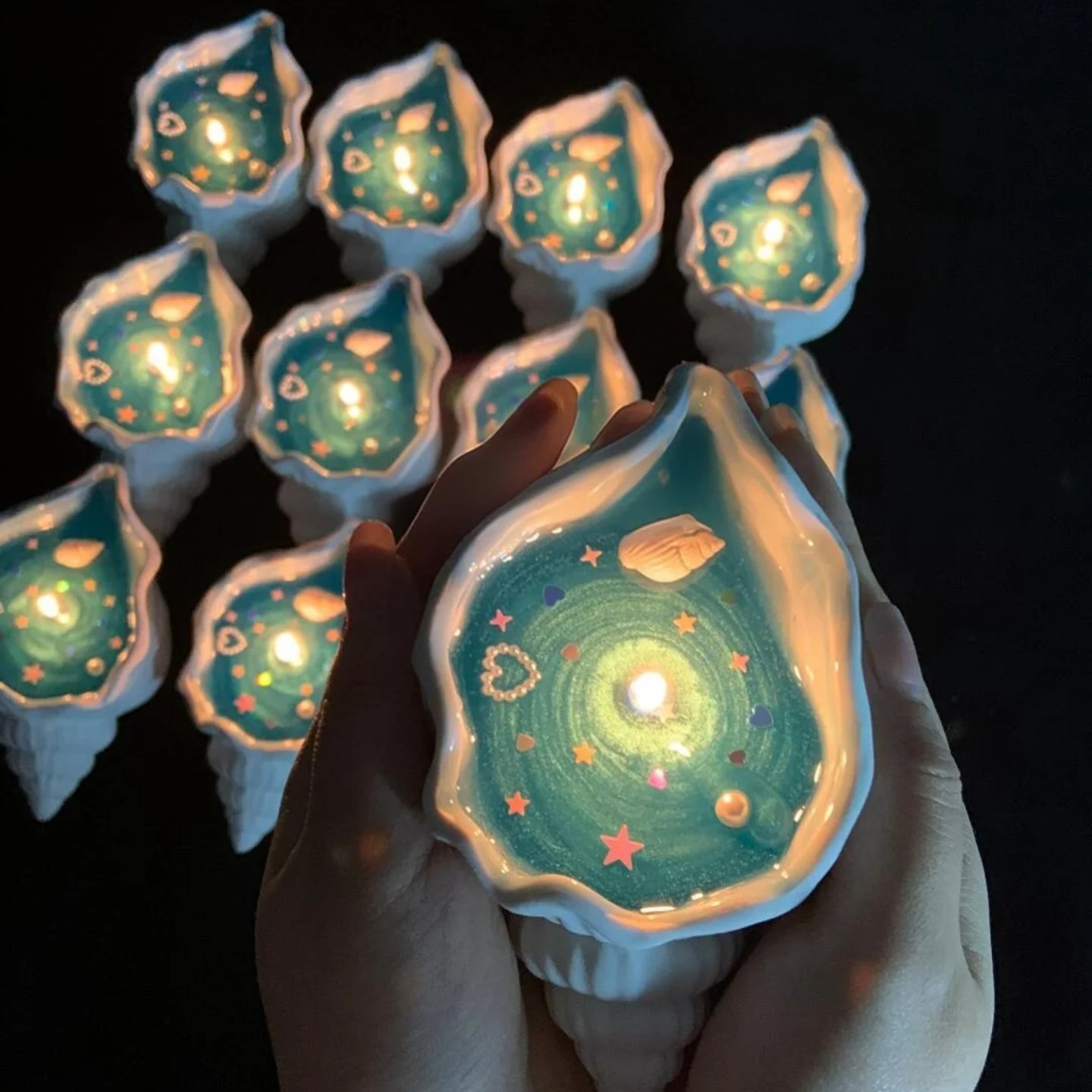 Holding handmade candles in the shape of seashells with both hands
